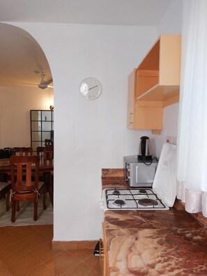 Una cocina compacta con estufa a gas, cafetera y un reloj en la pared.