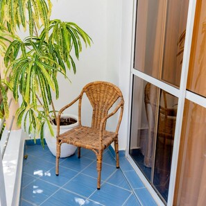 A wicker chair outside a building with a potted plant nearby. - Pine Breeze Holiday Resort (Mombasa)