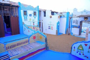 A colorful, themed children's play area with a slide, climbing wall, and a small stage. - Nubian Palace (Aswan)