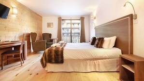 Ein Hotelzimmer mit Bett, Schreibtisch mit Stühlen, Fernseher und Balkonblick.