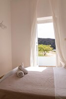 Un dormitorio con cama, ventana con cortinas y vistas al paisaje.