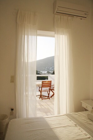 Une chambre à coucher avec un lit, une chaise et une vue sur un balcon équipé d’une chaise et d’une table.