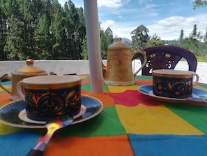 Une table recouverte d’une nappe colorée, avec une théière, une tasse et une soucoupe.
