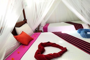 Une chambre avec deux lits, un baldaquin et une serviette rouge sur le sol.