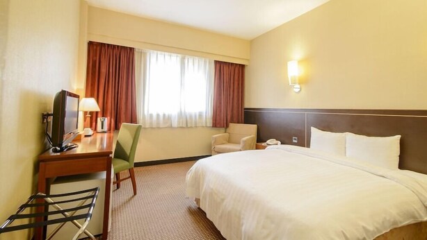 A hotel room with a bed, desk, chair, and a window with curtains. - San Hua Hotel (Kaohsiung)