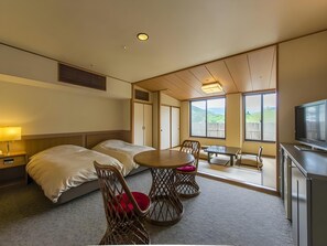 A hotel room with two beds, a dining table with chairs, a TV, and large windows with a view. - Mizunosato Marukyu Ryokan (Izu)