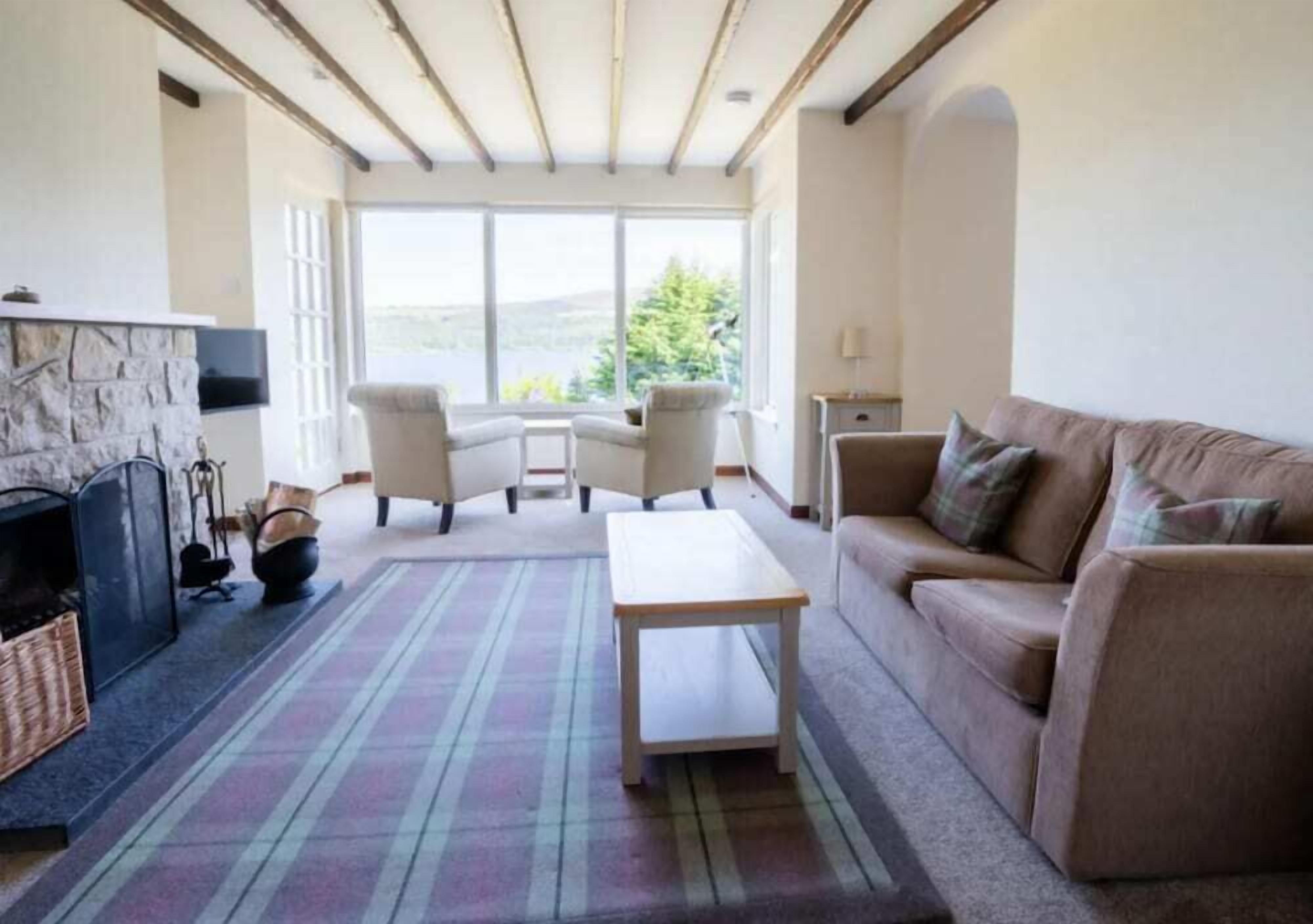 Una sala de estar acogedora con chimenea, un sofá, una mesa de centro y vistas al exterior.