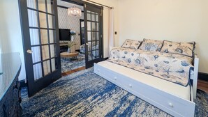 A bedroom with a bed, a large window, and a door leading to another room. - Updated 4BR/2BA Victorian - Linens Included, Beach Box, Walkable, Off-Street Parking (West Cape May)