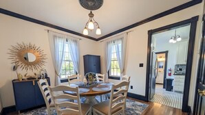 A dining area with a round table, chairs, a blue cabinet, and a chandelier. - Updated 4BR/2BA Victorian - Linens Included, Beach Box, Walkable, Off-Street Parking (West Cape May)