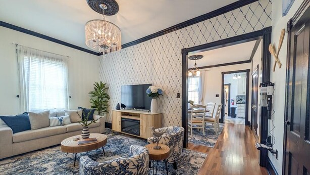 A living room with a sofa, armchairs, a TV, and a chandelier. - Updated 4BR/2BA Victorian - Linens Included, Beach Box, Walkable, Off-Street Parking (West Cape May)