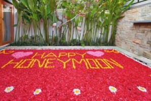 A red carpet with 'HAPPY HONEYMOON' written in yellow, surrounded by green plants and a stone wall. - The Jimbaran Beach Villa by Ini Vie Hospitality (Jimbaran)