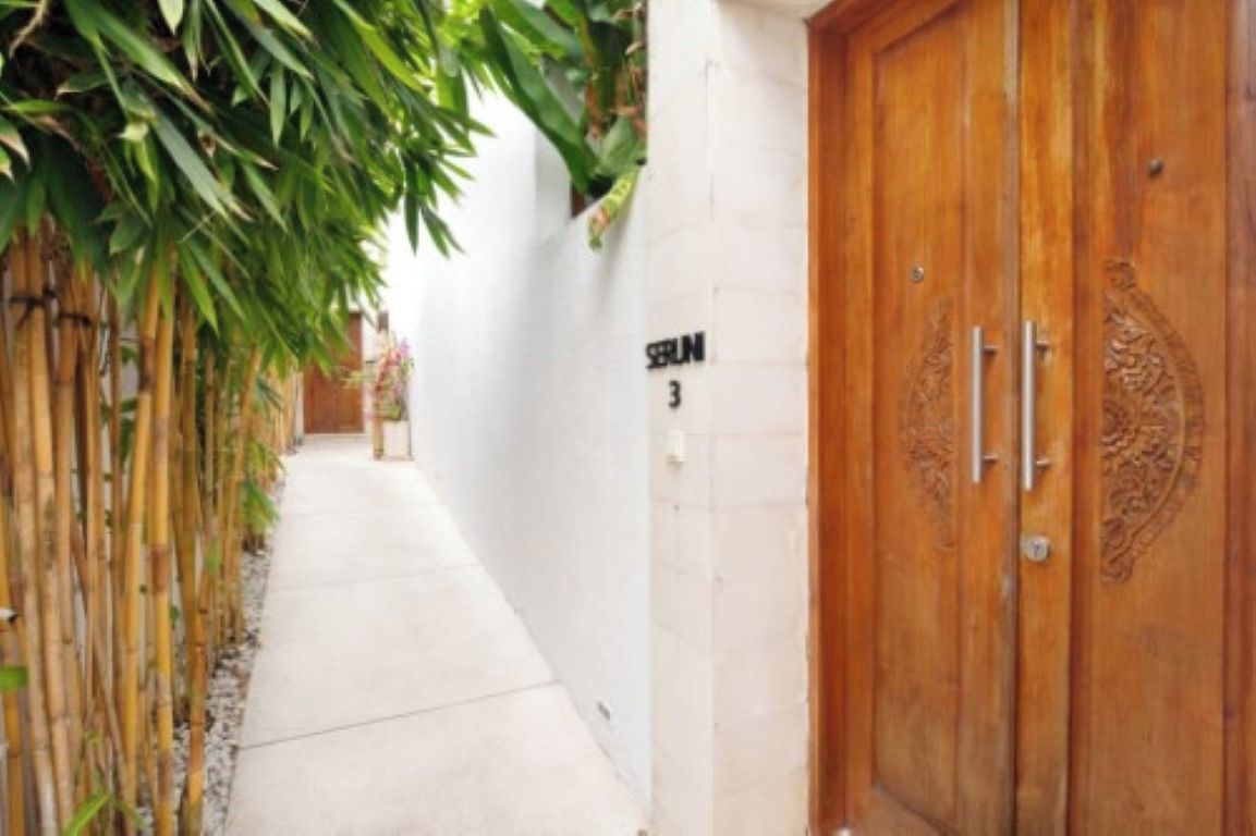 A narrow corridor with a bamboo fence on one side and a wooden door with a number '3' on the wall.