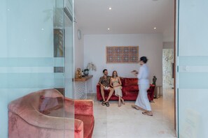 Un salon moderne avec un canapé rouge, une cloison en verre et un élément décoratif mural.