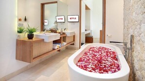 A modern bathroom with two sinks, a large mirror, a bathtub filled with rose petals, and two wall-mounted televisions labeled 'Netflix'. - The Jimbaran Beach Villa by Ini Vie Hospitality (Jimbaran)