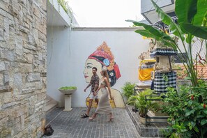 Une cour avec un mur en pierre, une fresque murale et des plantes en pot.