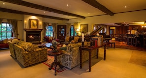 A spacious living room with a fireplace, a grand piano, and a dining area with a bar.