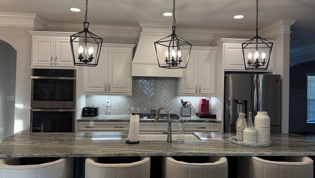 A modern kitchen with white cabinets, a marble countertop, stainless steel appliances, and pendant lighting. - Spacious 4Bd/4bath Home with Media Room-Great for Master’s Week! (Evans)
