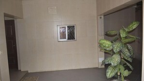 A hallway with a potted plant, a framed picture on the wall, and a door leading to another room. - Hotel La Citadelle (Abidjan)