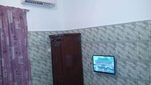 A room with a patterned wall, a wooden door, and a television mounted on the wall. - Hotel La Citadelle (Abidjan)