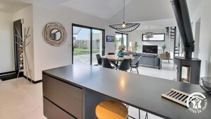 Een moderne keuken met een centraal eiland, een eethoek en een open haard.