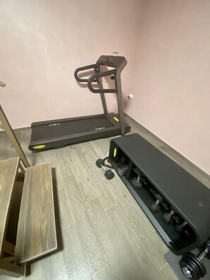 Une pièce équipée d’un tapis de course, d’un banc et d’un banc de musculation.