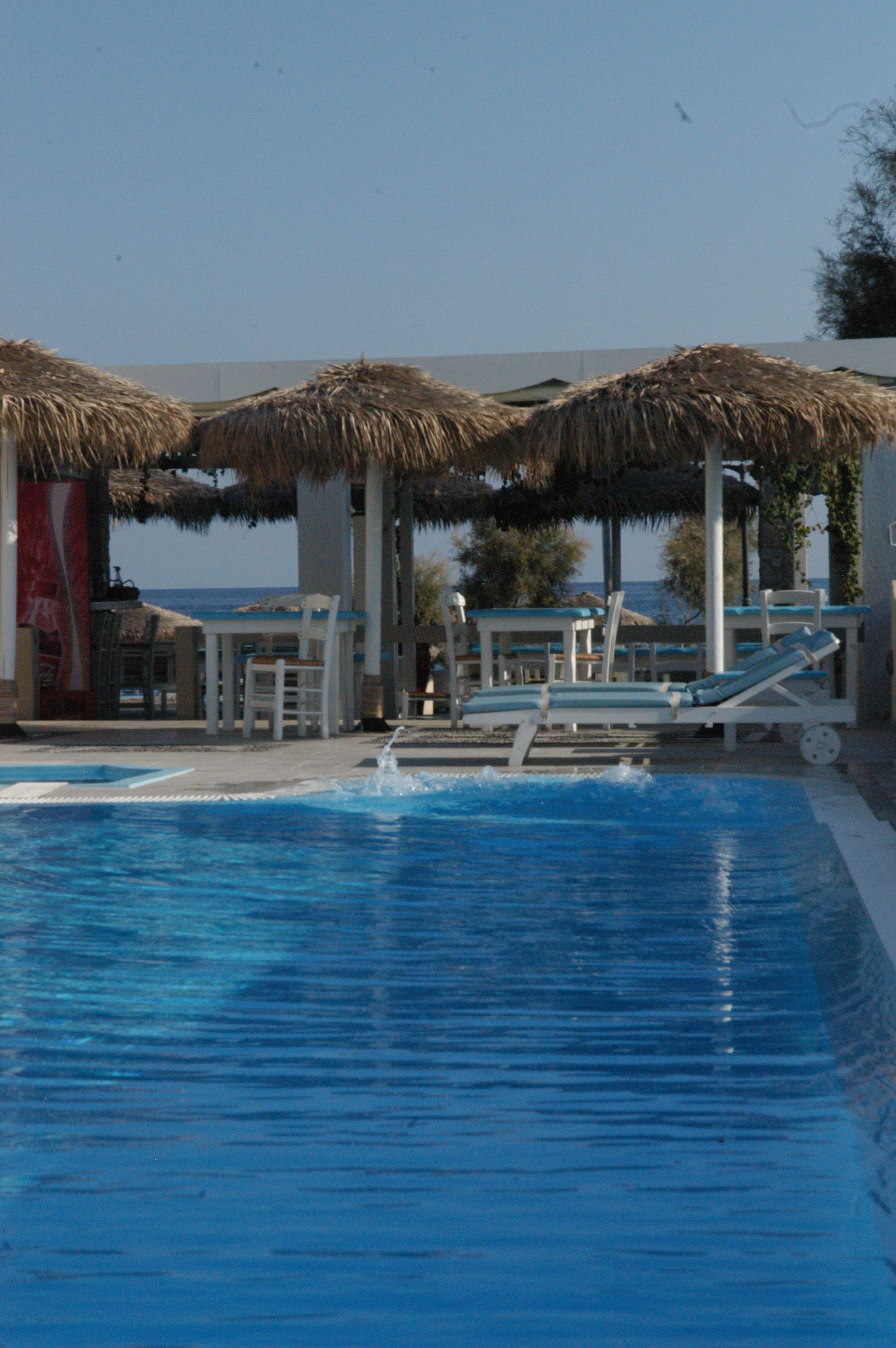 A swimming pool with lounge chairs and umbrellas, a table, and a flag.