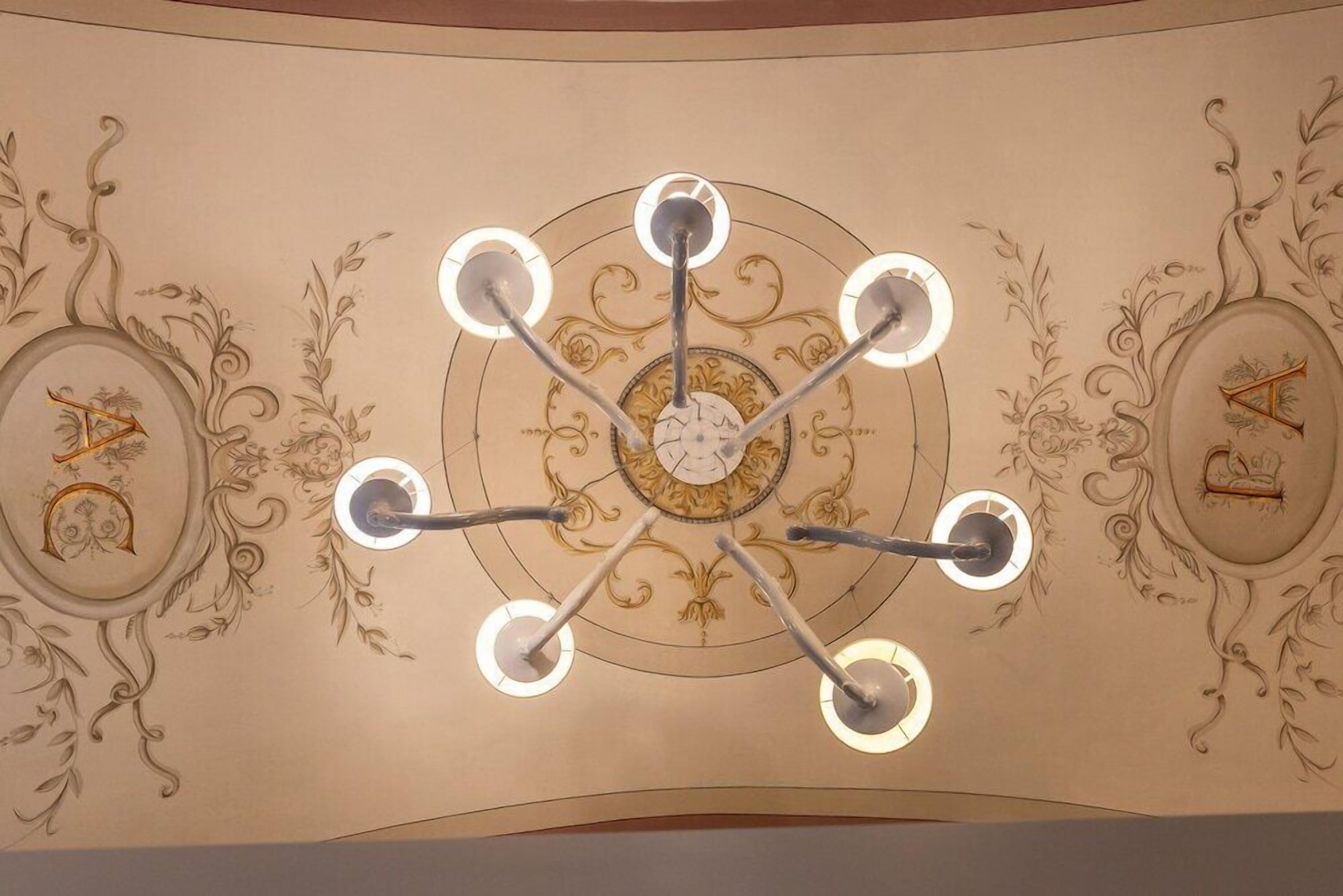 Un techo con una lámpara central y decoraciones ornamentales en las paredes.