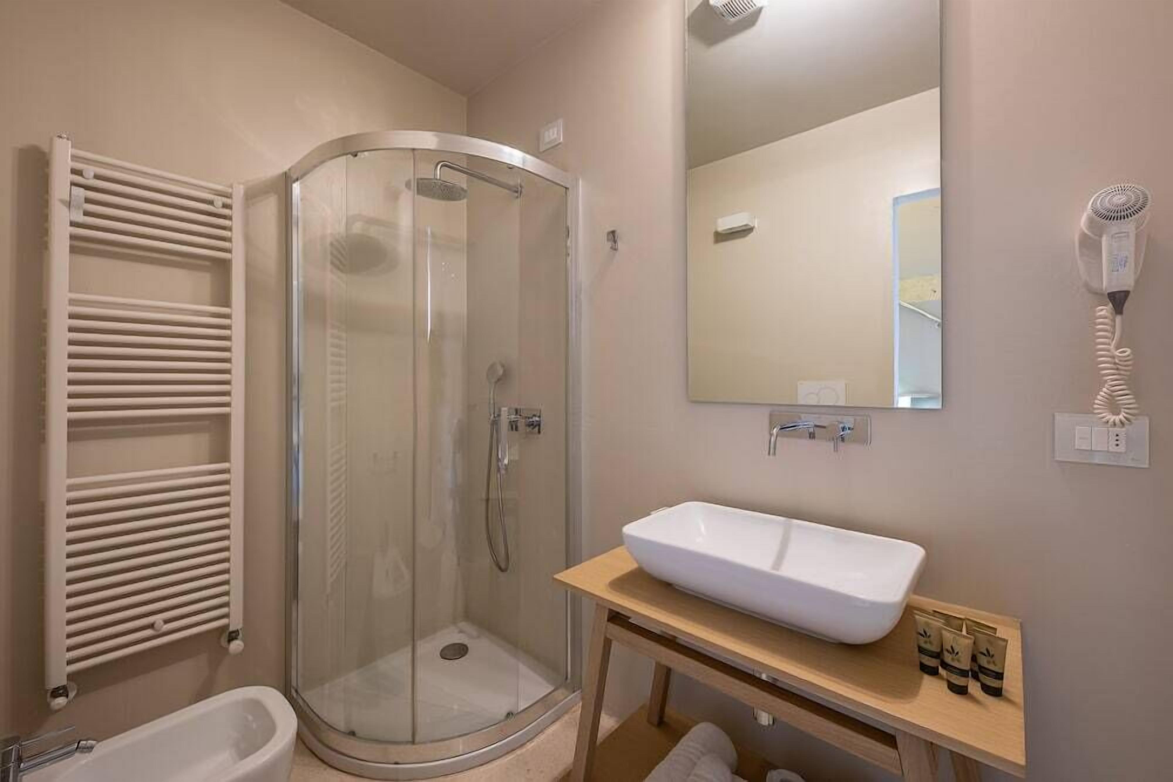 A modern bathroom with a glass-enclosed shower, a white sink, and a towel rack.