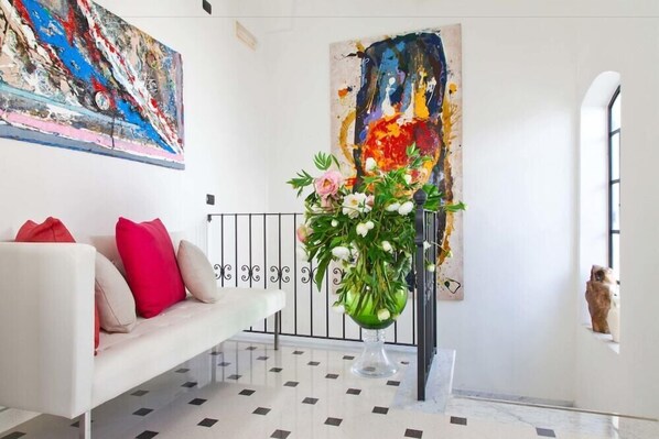 A modern living room with a white sofa, red cushions, a glass vase with flowers, and abstract paintings on the walls. - Palazzo Arco Cadura Hotel & Spa (Galatina)
