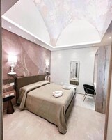 Un dormitorio moderno con una cama grande, lámparas de noche, un espejo y un pequeño escritorio.