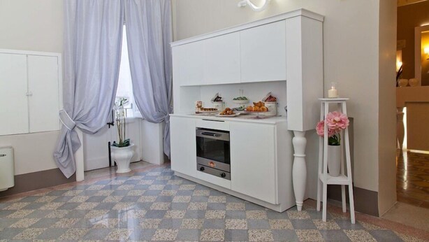 Een compacte keuken met een ingebouwde oven, een wit kastje en een klein aanrecht met decoratieve objecten.