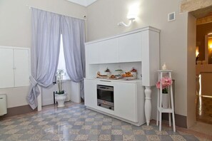Une cuisine compacte dotée d’un four encastré, d’un meuble blanc et d’un petit plan de travail agrémenté d’objets décoratifs.