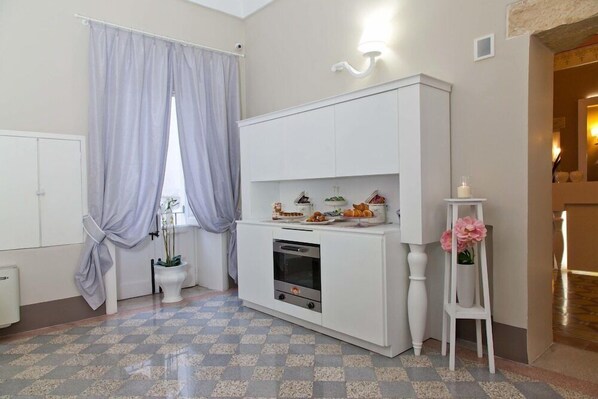 A compact kitchen with a built-in oven, a white cabinet, and a small countertop with decorative items. - Palazzo Arco Cadura Hotel & Spa (Galatina)