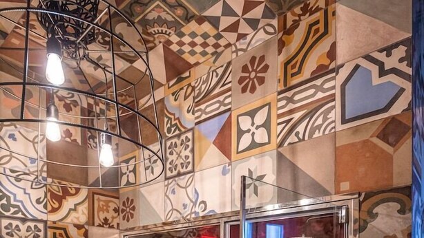 A bathroom with a shower enclosed in glass, surrounded by patterned tiles. - Palazzo Arco Cadura Hotel & Spa (Galatina)