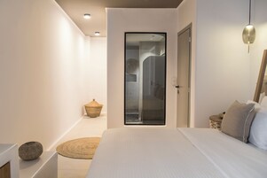 Un dormitorio moderno con una cama grande, un vidrio que da al baño y una pequeña cesta de mimbre en el suelo.