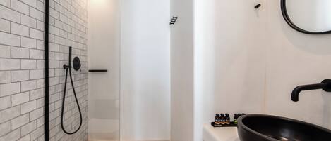 A modern bathroom with a glass-enclosed shower, a black sink, and a mirror on the wall.