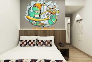 A hotel room with a bed, a nightstand, and a wall with a colorful mural. - Front One Cabin Malioboro Jogja (Yogyakarta)