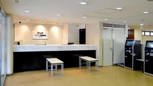 A hotel reception area with a reception desk, two small tables, a glass door, and a self-service kiosk. - Hotel Raffinato Sapporo (Sapporo)