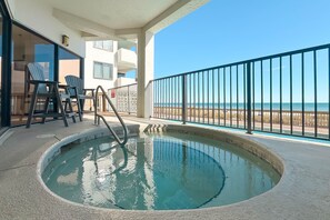 A swimming pool with a view of the beach, a covered seating area with chairs, and a railing. - Broadmoor 705 | Beachfront | Pool & Hot Tub | My Beach Getaways (Orange Beach)