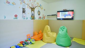 Une salle de jeux pour enfants avec une télévision, des jouets et un fauteuil poire.