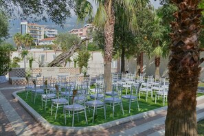 Una terrazza con file di sedie bianche e un muro a scacchi.