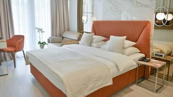 Una habitación de hotel moderna con una cama grande, una mesita de noche con teléfono, una silla, un escritorio y una planta en maceta.