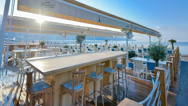 A seaside restaurant with outdoor seating, a bar area, and a view of the beach and sea. - Mediteran Wellness & Spa, Congress Center (Bečići)