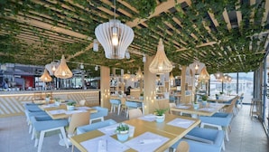 A restaurant with multiple tables, hanging lights, and a ceiling with greenery. - Mediteran Wellness & Spa, Congress Center (Bečići)