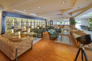 A spacious lounge area with multiple seating options, a wine display, and a large window providing natural light. - Mediteran Wellness & Spa, Congress Center (Bečići)