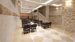 A spacious hall with a checkered floor, patterned chairs, and a staircase. - Mediteran Wellness & Spa, Congress Center (Bečići)