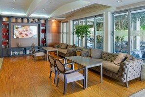 A spacious living area with a sofa set, a dining table, chairs, a bookshelf, and a television. - Mediteran Wellness & Spa, Congress Center (Bečići)