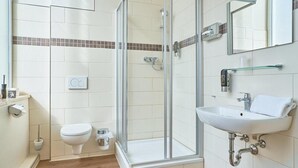 A bathroom with a glass-enclosed shower, a white sink, and a toilet. - eXo Individual Hotel Mannheim - by Superfly Hotels (Mannheim)