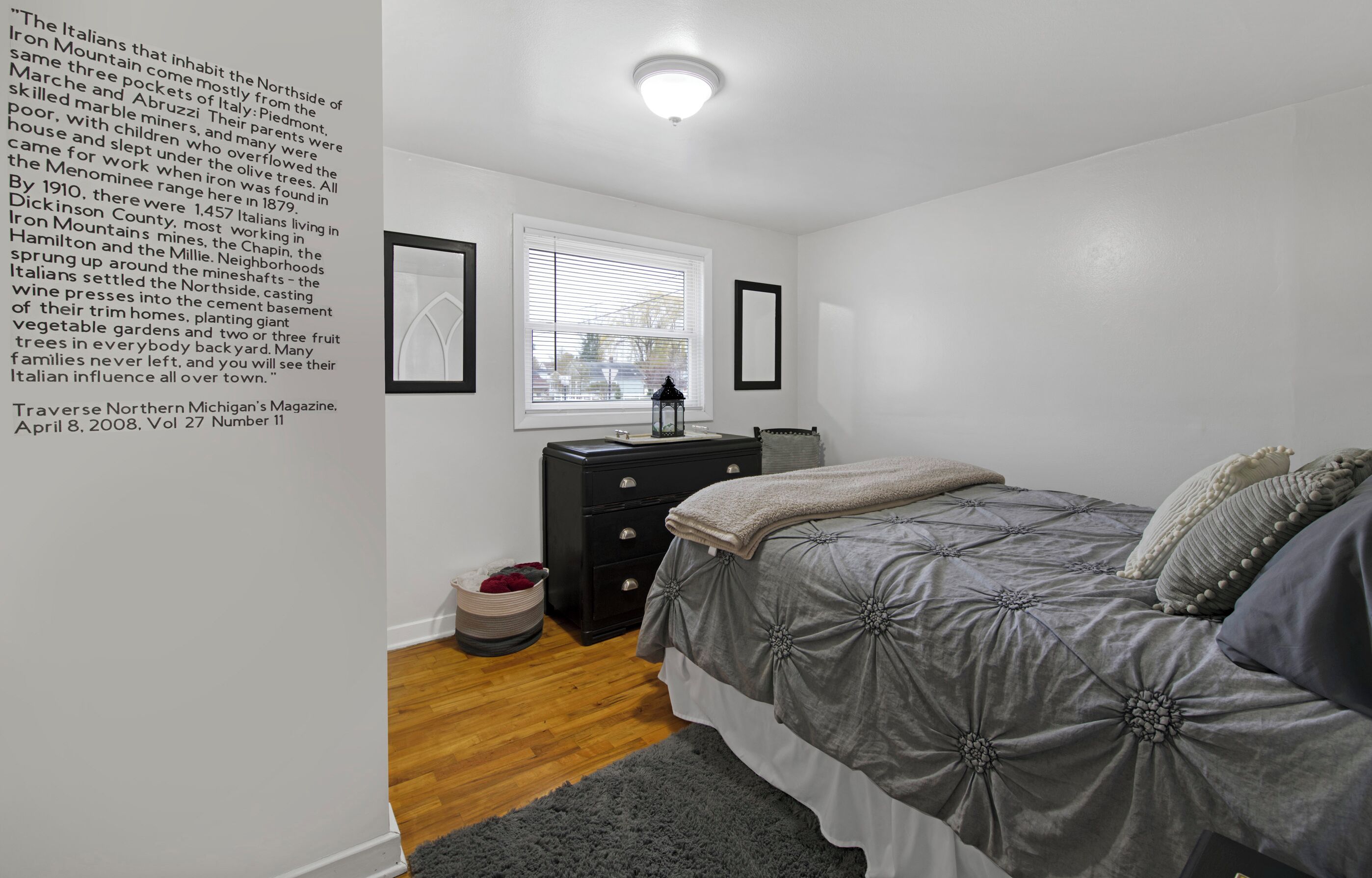 A bedroom with a bed, dresser, and window.