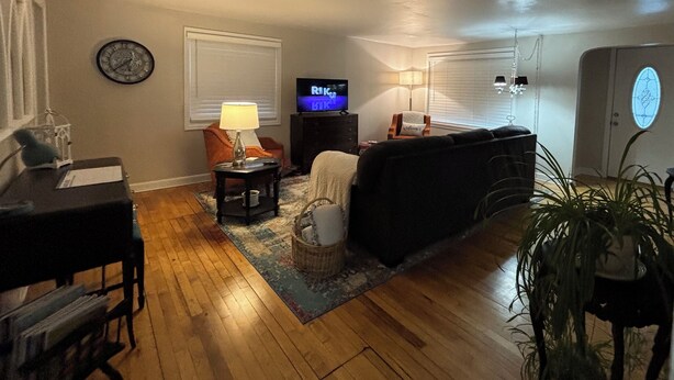 Una sala de estar con sofá, televisor, lámpara y piano.